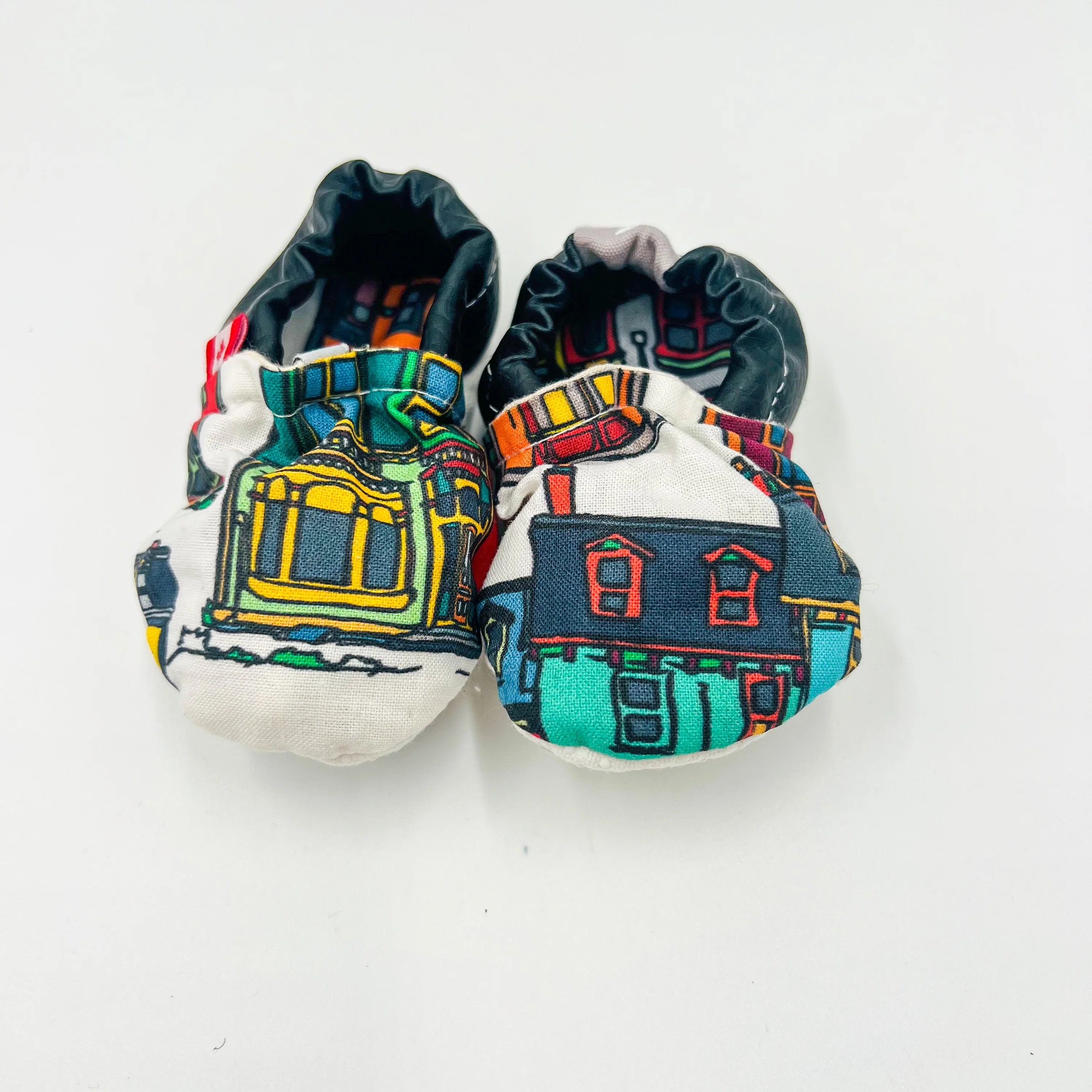 Pair of baby shoes with colourful Newfoundland row house designs on a white background