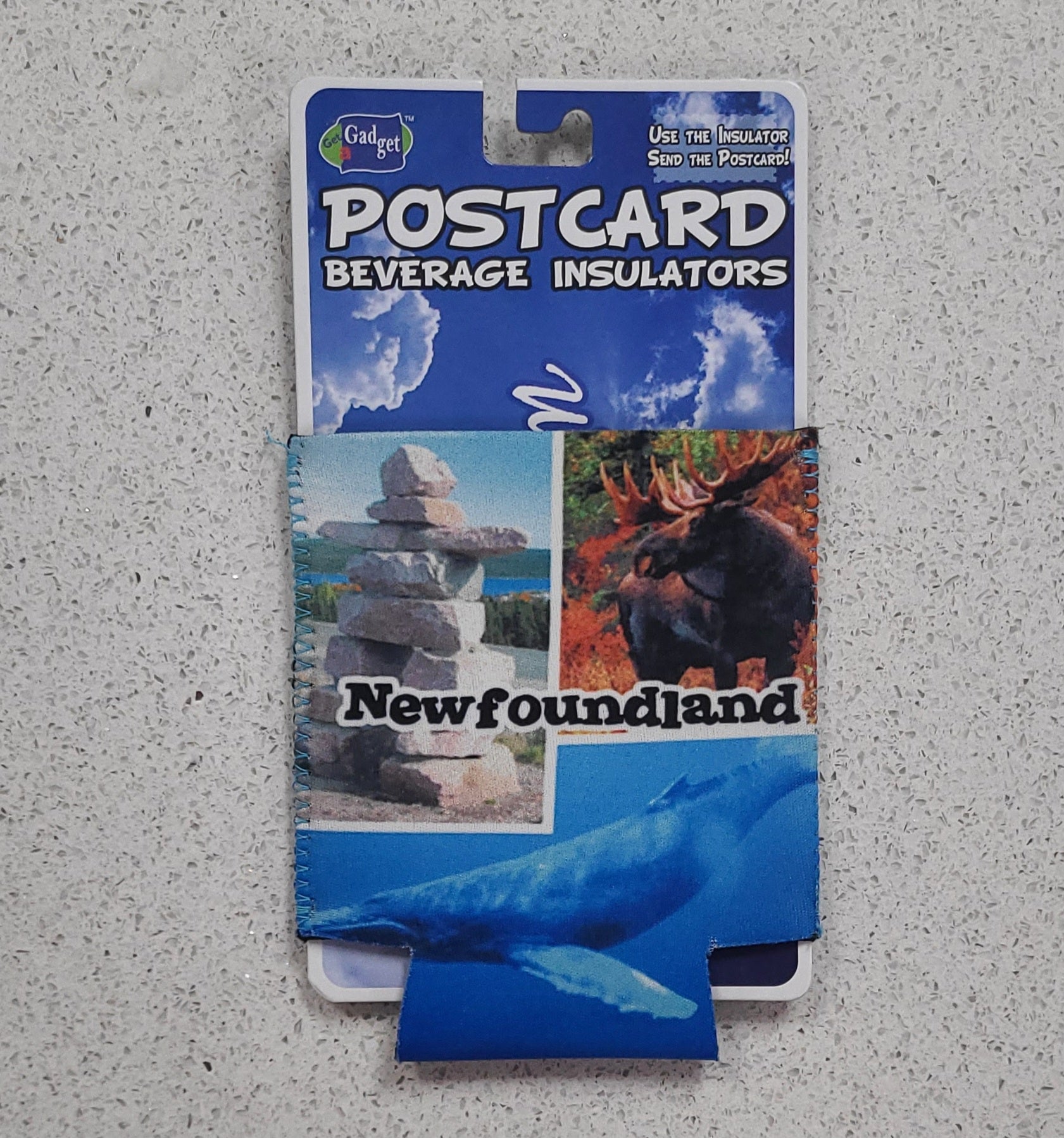 Packaged beverage insulators with Newfoundland-themed images on a gray surface