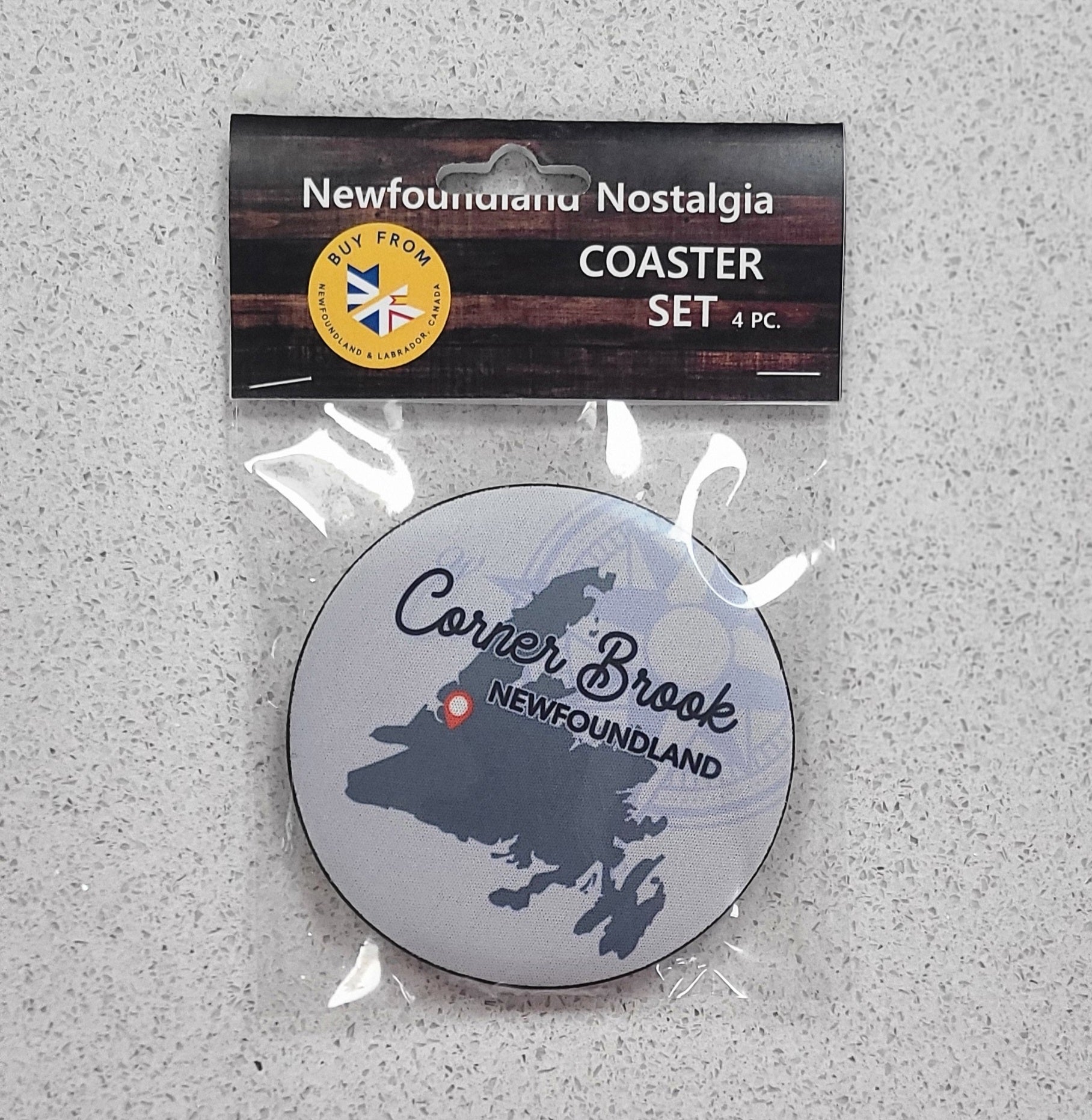 Coaster set with 'Corner Brook Newfoundland' design on a gray surface, featuring packaging labeled 'Newfoundland Nostalgia'.