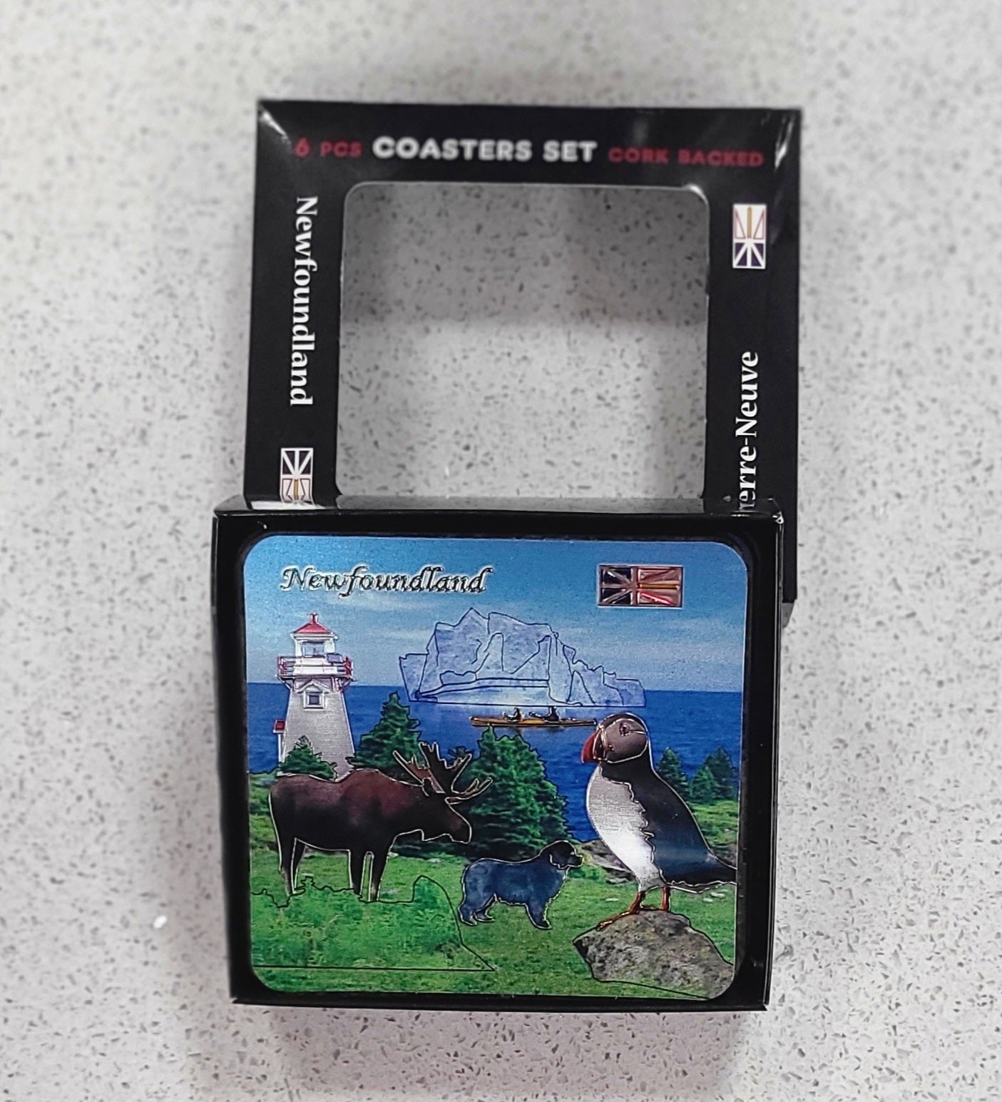 Packaged coaster set with Newfoundland-themed design on a textured surface