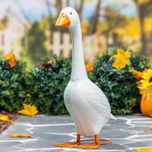 Decorative goose statue on a stone path with blurred garden background