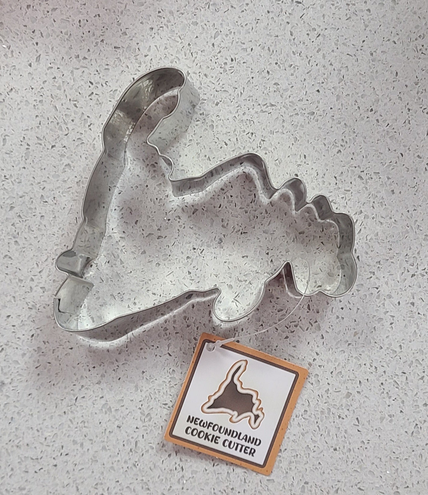 Metal Newfoundland cookie cutter on a gray surface with a Newfoundland logo tag.