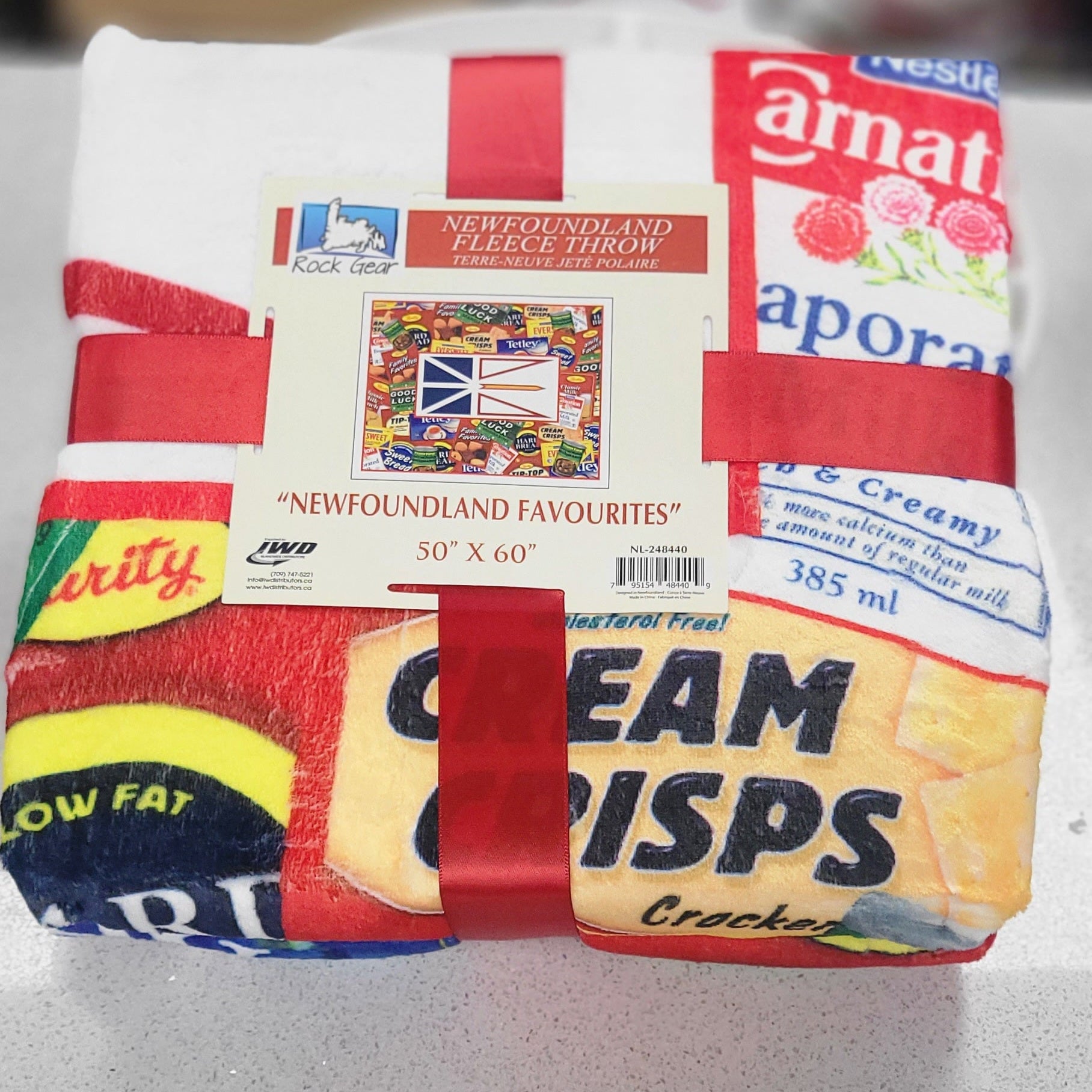 Fleece throw blanket with Newfoundland-themed packaging on a white surface