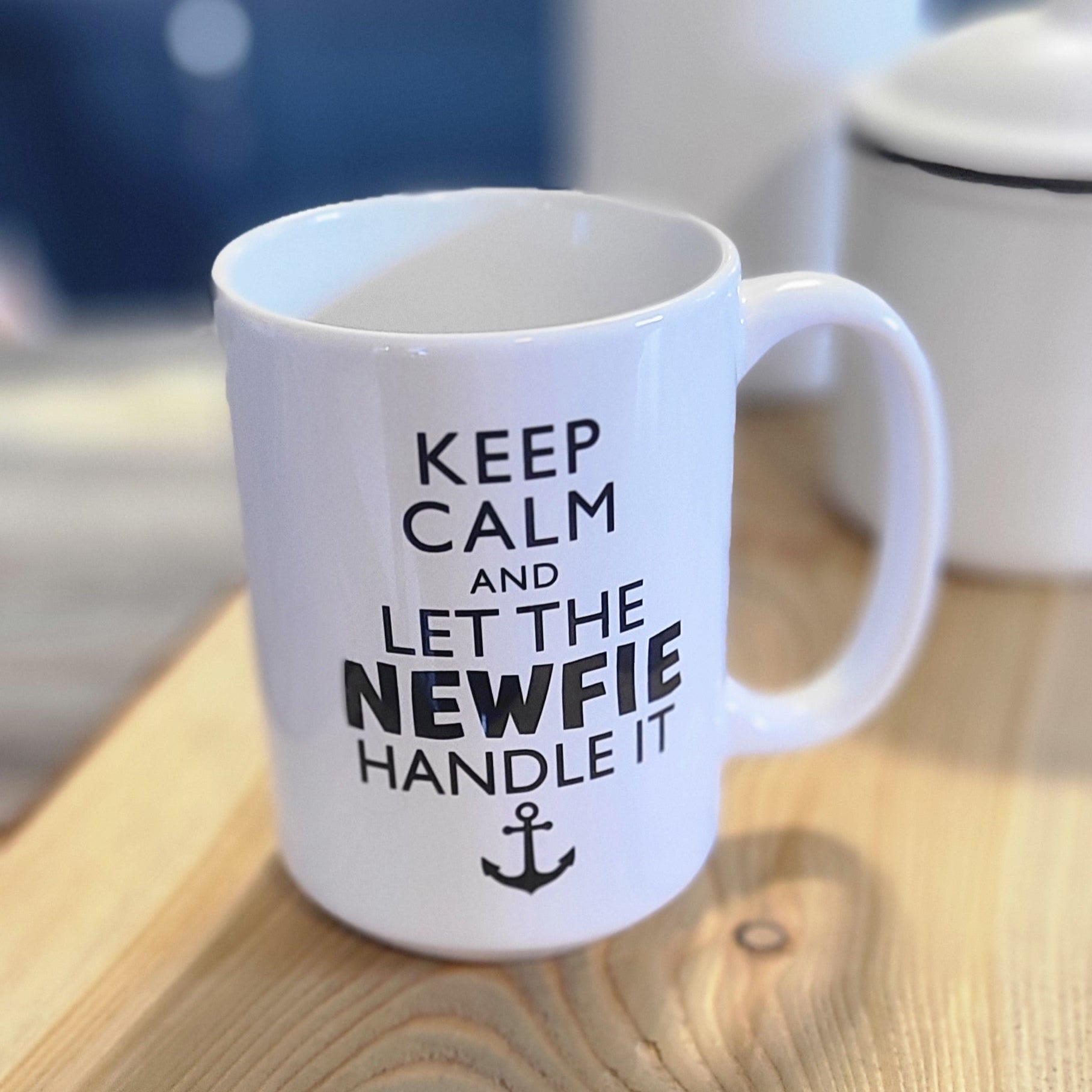 White ceramic mug with the phrase “Keep calm and let the Newfie handle it” in black text with an anchor symbol.
