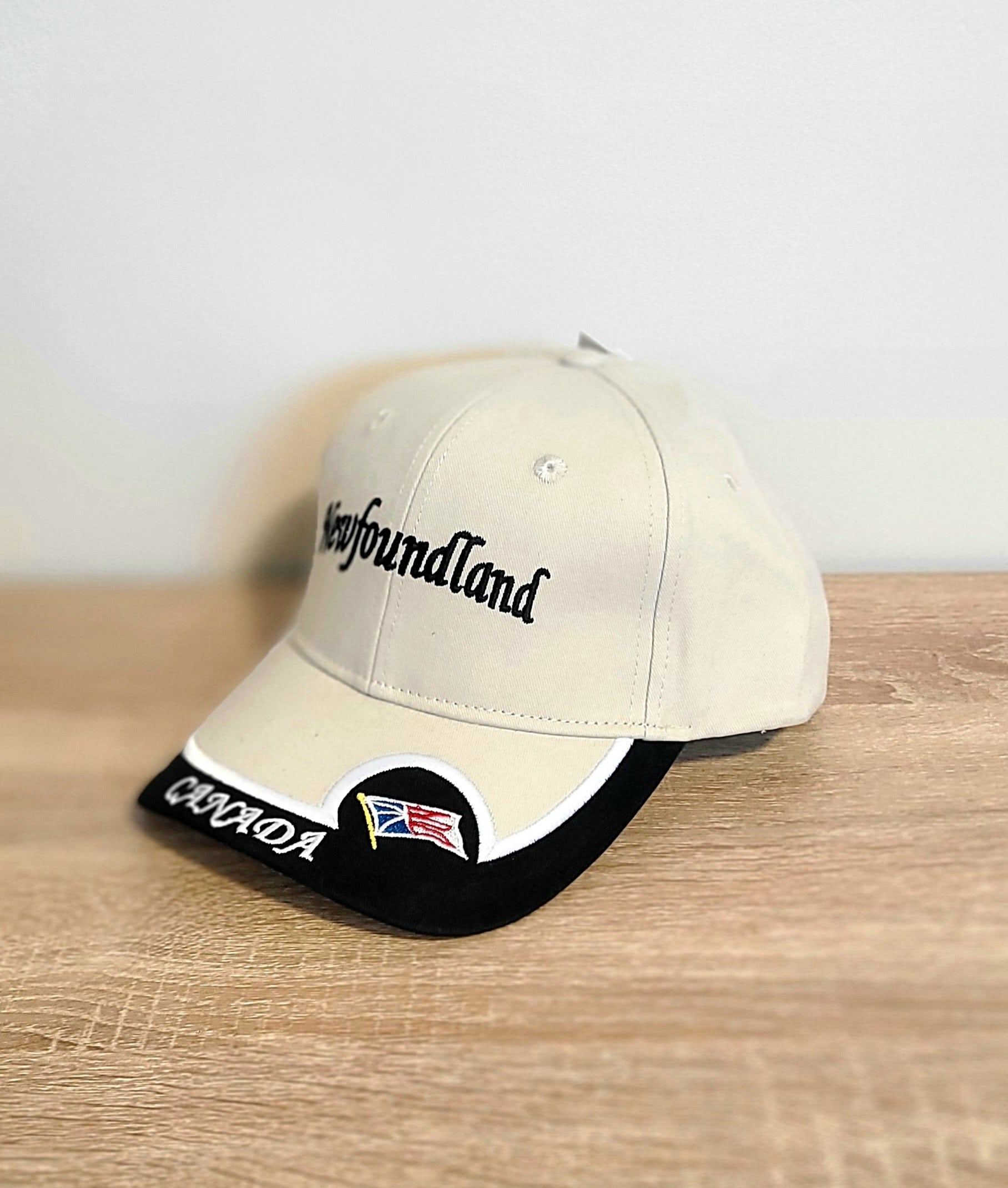 Beige cap with 'Newfoundland'  and Canada text and flag on a wooden surface