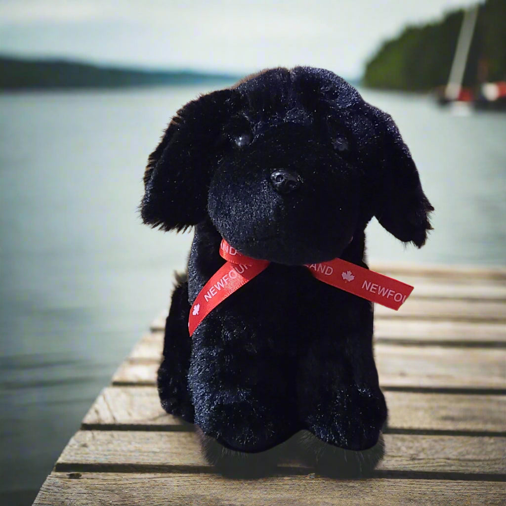 Black Plush Dog with a red bow tie on a sunflower-patterned cushion on a bench