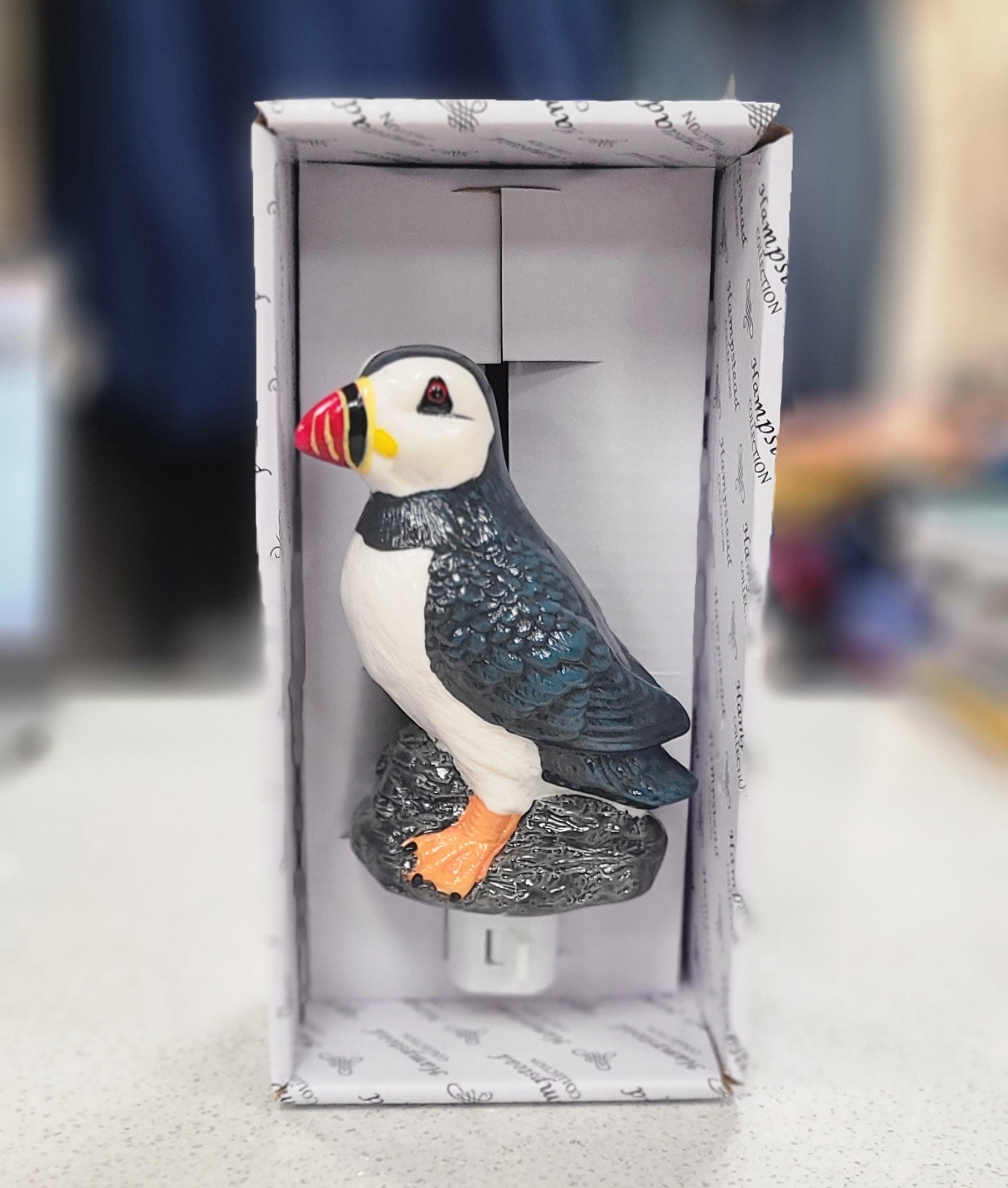 Puffin-shaped night light in a box on a marble surface