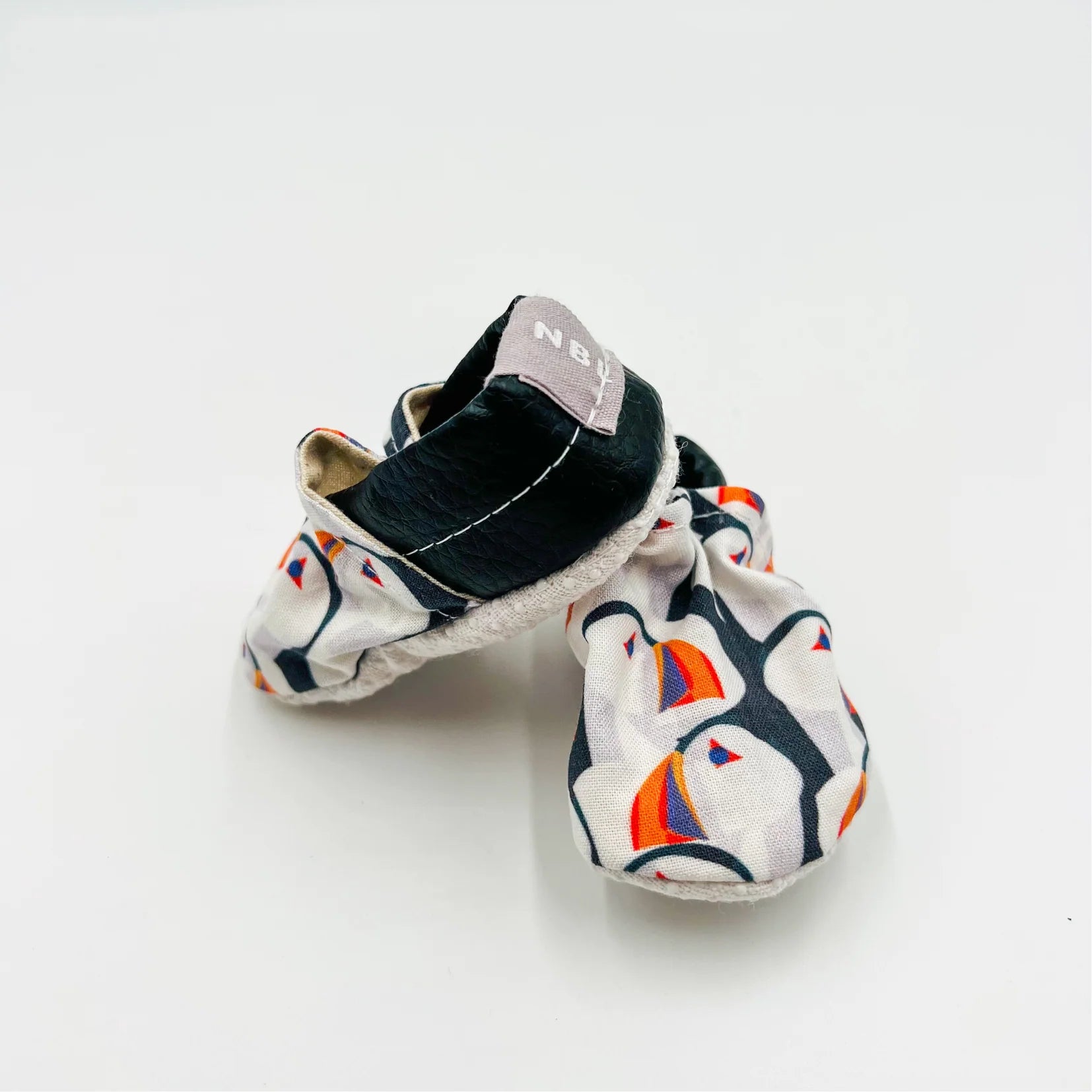 Pair of baby summer shoes with colourful Newfoundland puffin patterns on a white background