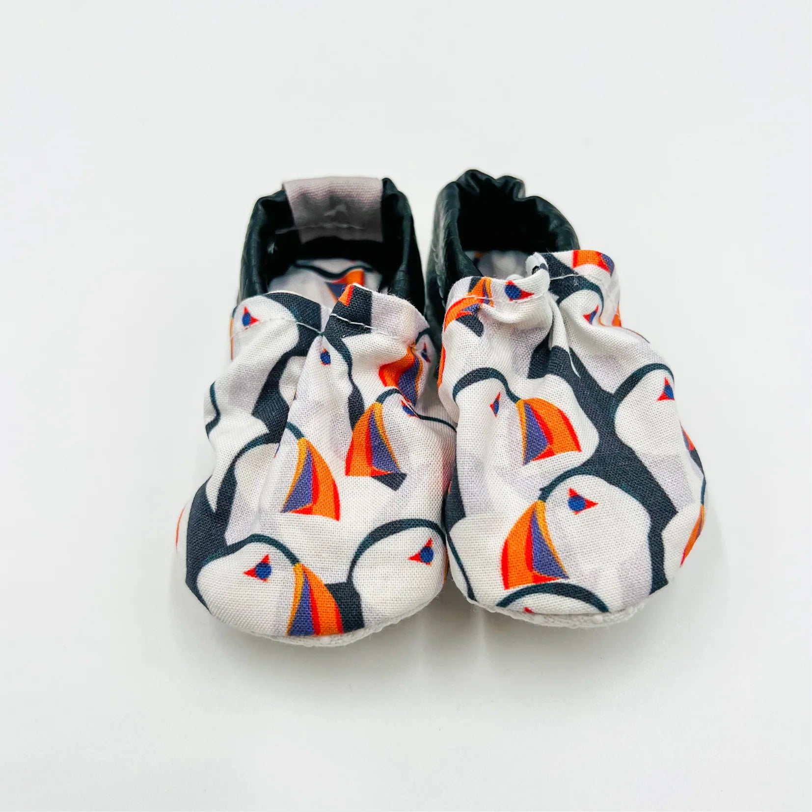 Pair of infant summer shoes with famous Newfoundland puffin pattern on a white background