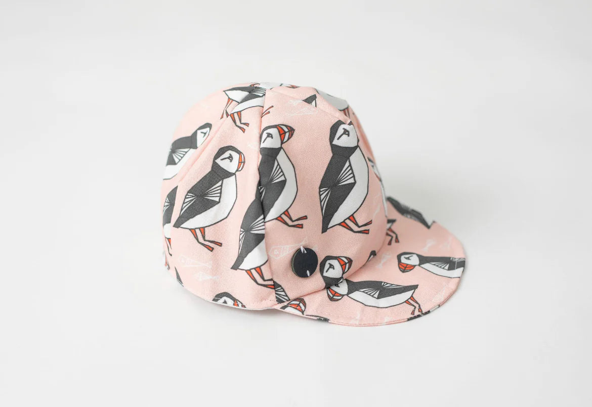 Pink baseball cap with Newfoundland's puffin pattern on a white background