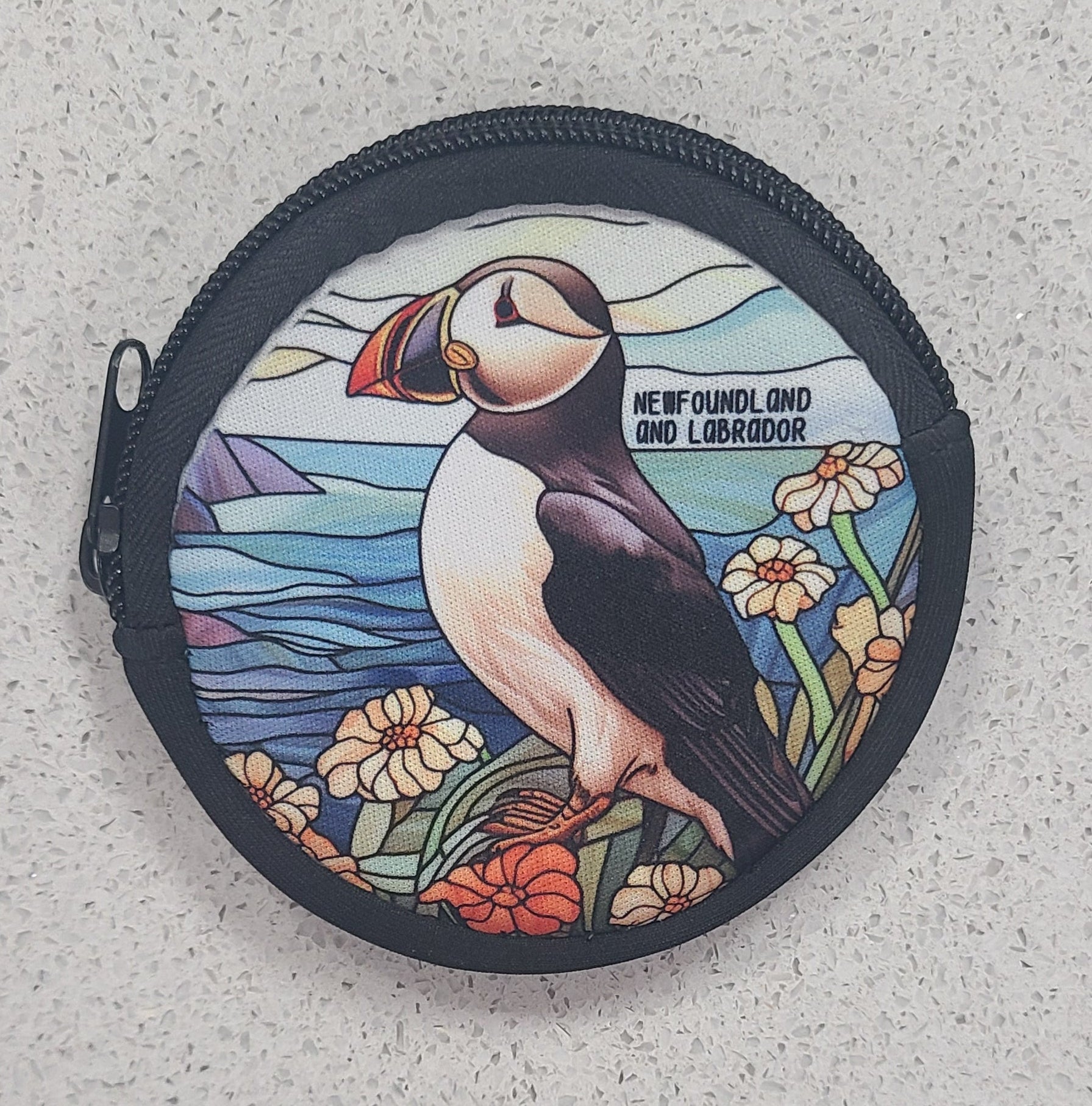 Round purse with a puffin design on a textured surface