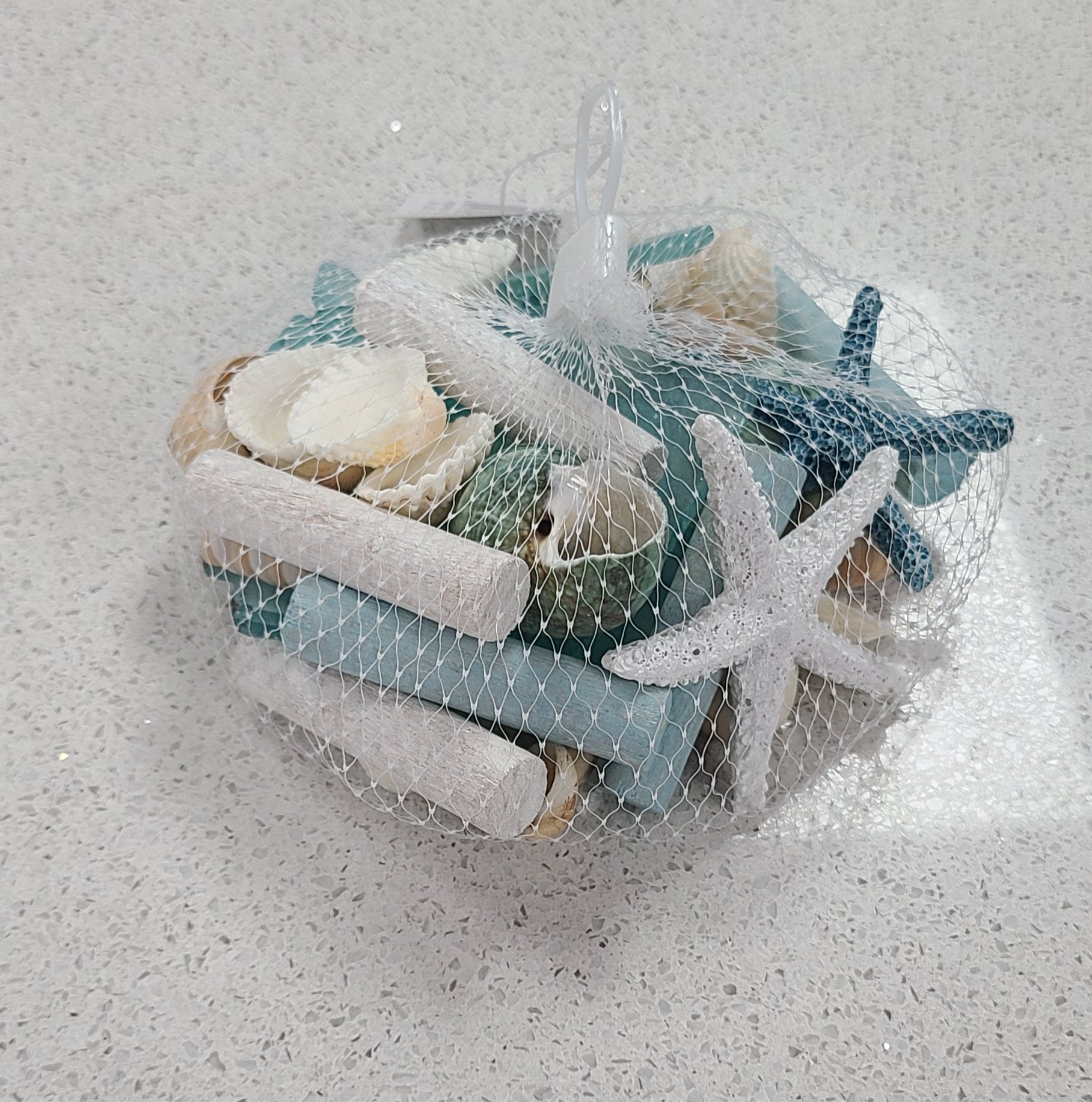 Decorative basket with seashells, starfish, and blue coral on a textured white background