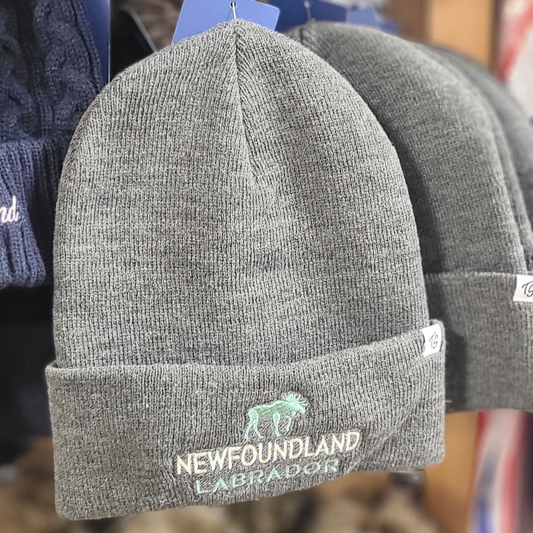 Gray knit hats with Newfoundland and Labrador branding on a display rack.