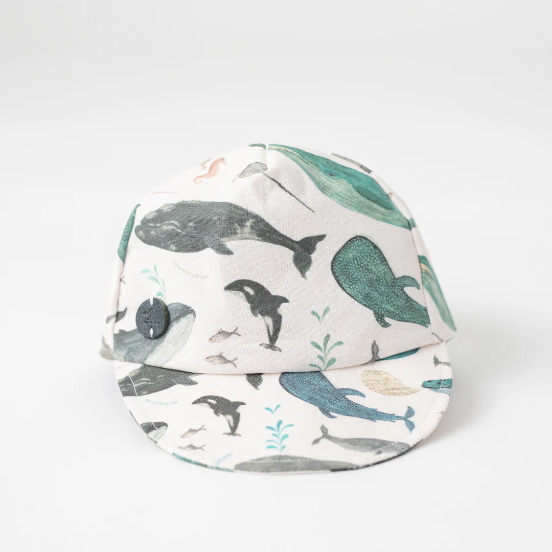 Infant Whale Baseball Cap decorated with famous Newfoundland whales and narwhals, front view.