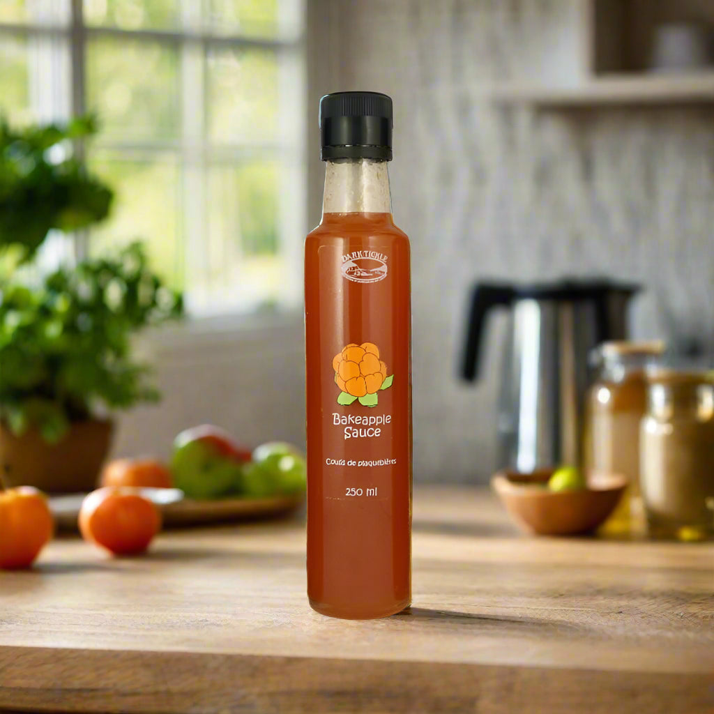 Tall 250 ml bottle of Newfoundland Bakeapple Sauce with berry illustration on wooden kitchen countertop