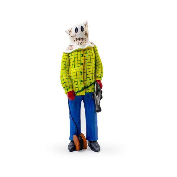 Newfoundland figurine of a mummer character wearing a yellow checkered shirt and blue pants on a white background