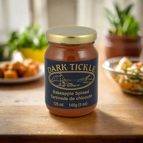125 ml jar of Newfoundland Bakeapple Spread on a wooden countertop with appetizers in the background.