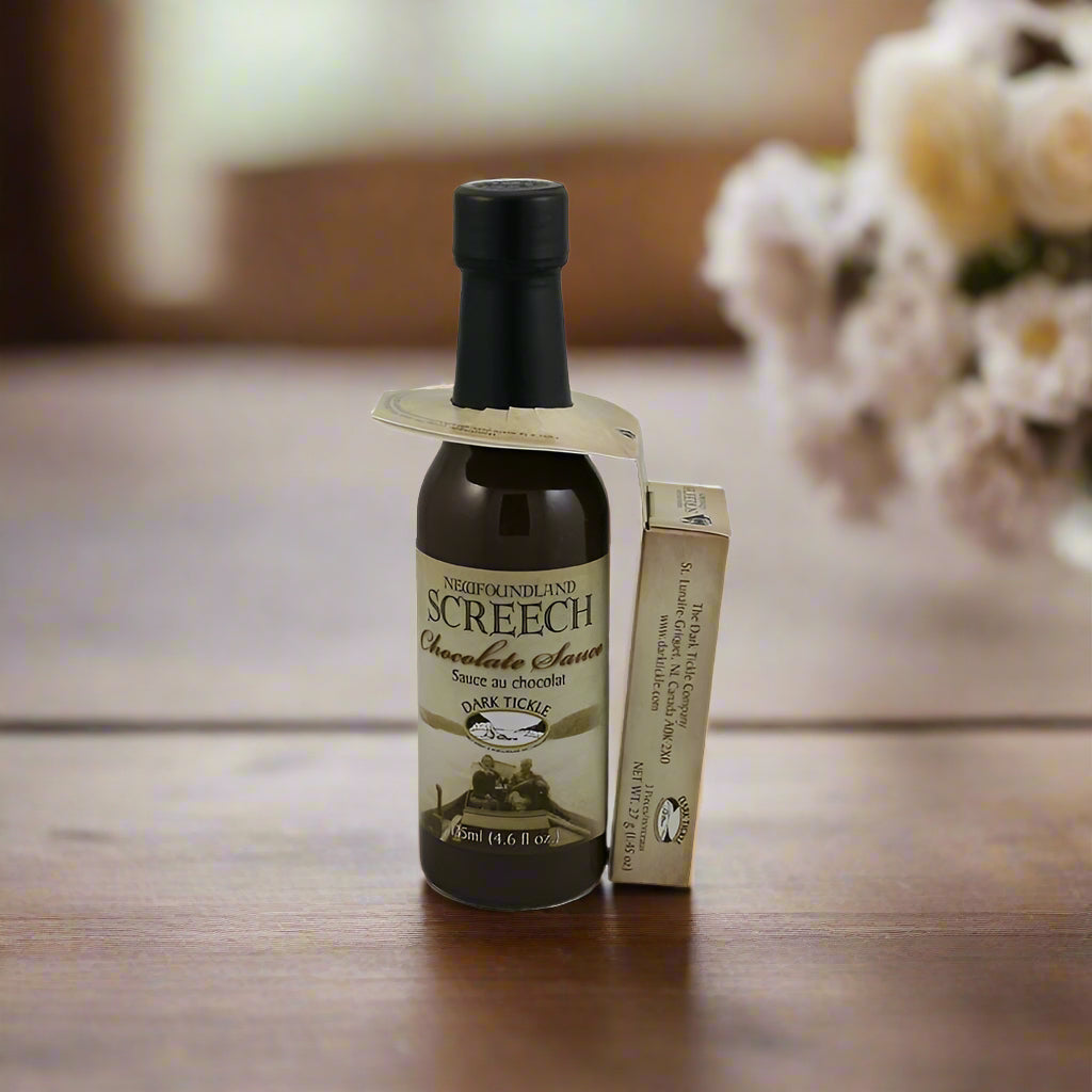 Bottle of Newfoundland Screech Sauce & Chocolate on a wooden table with blurred flowers in the background