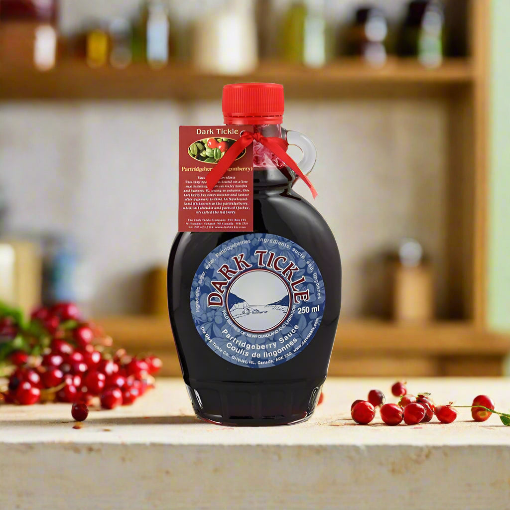 Jug bottle of Dark Tickle partridgeberry syrup with a red label on a blurred background