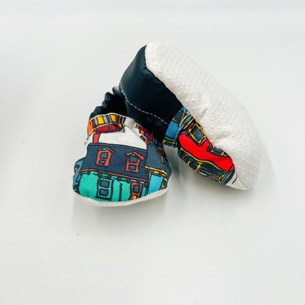 Bottom view of baby summer shoes with a colourful Newfoundland row houses print and white anti-slip soles.